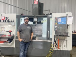 Leighton Jones in front of a machine at Jones Machining Company LLC